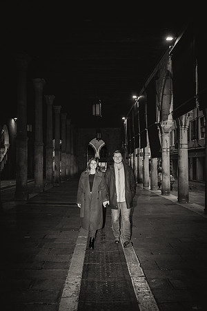 Silhouetted couple walking hand in hand through a Venetian street.