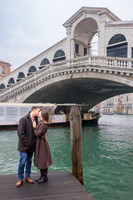 Couple standing beneath the Rialto Bridge, celebrating their engagement.