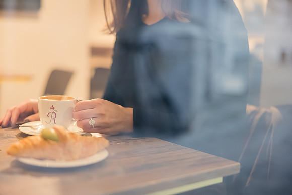 Close-up of an engagement ring resting near a coffee cup.