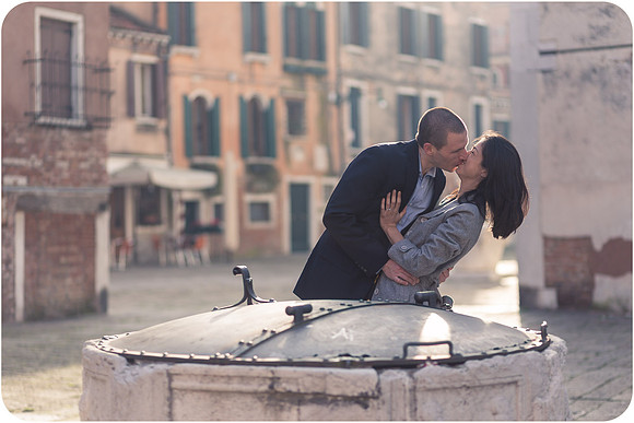 A couple posing by the water in a Venetian winter setting