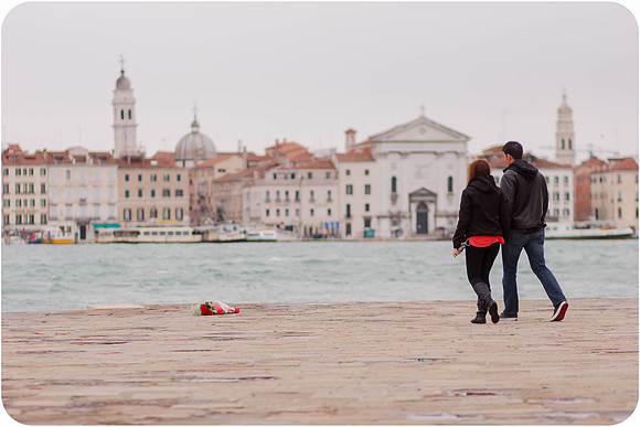 Couple standing near the water with the Venice skyline in the background.