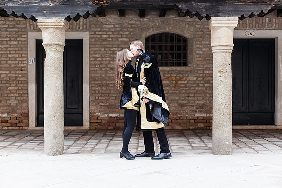 Masked couple in an archway during Venice Carnival.
