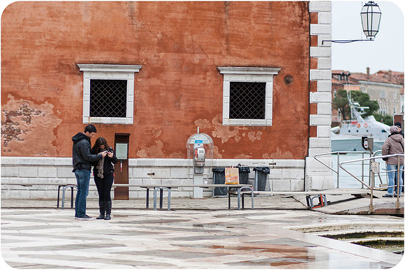 Couple walking along a quiet Venetian street near the waterfront.