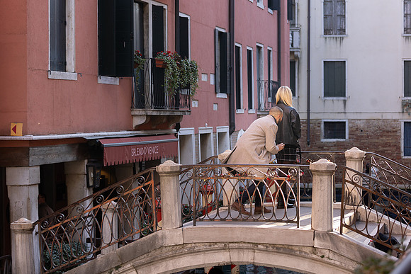 A man proposes on a charming Venetian bridge as the sun sets, capturing a once-in-a-lifetime moment.