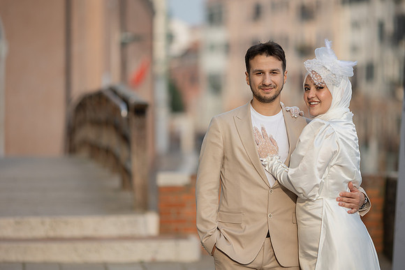 Engaged couple posing on a Venetian bridge with scenic views.