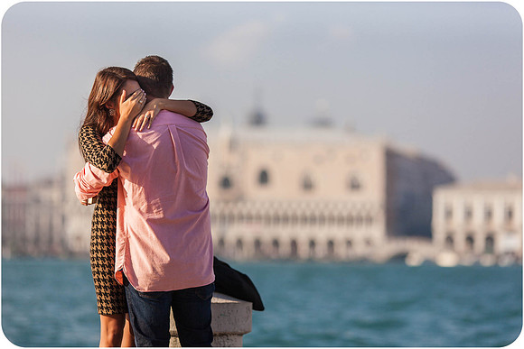 A newly engaged couple walks hand-in-hand along the Venetian waterfront.