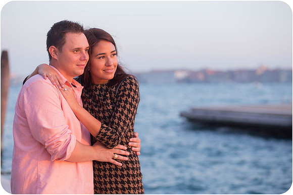 A newly engaged couple shares a tender embrace by the Venetian lagoon.