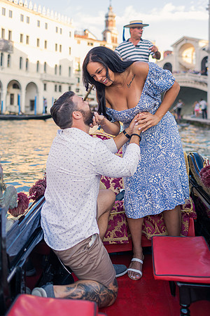 Fiancé kneeling during gondola proposal in Venice