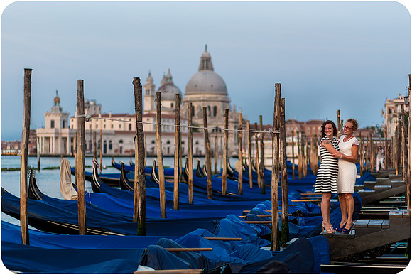 Mother and daughter walking by the gondolas in Venice during a peaceful morning.