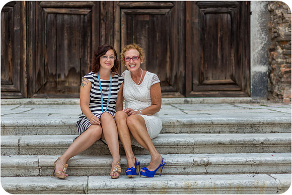 Mother and daughter sitting by a historic wooden door in Venice, enjoying their family photo session.