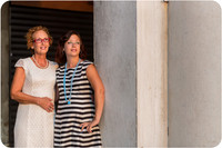 Mother and daughter standing by Venetian columns, enjoying the morning light.