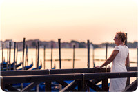 Mother and daughter standing by the gondolas at sunrise, with a golden glow over Venice.