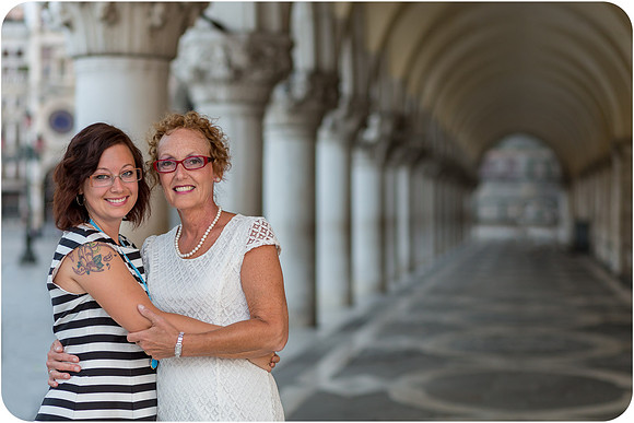 Mother and daughter standing under Venetian arches near Doge's Palace in Venice.