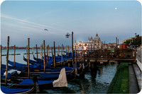 Gondolas on the water at sunrise in Venice, capturing the serene morning atmosphere.