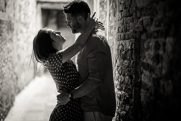 Couple embracing passionately in a quiet alleyway in Venice.
