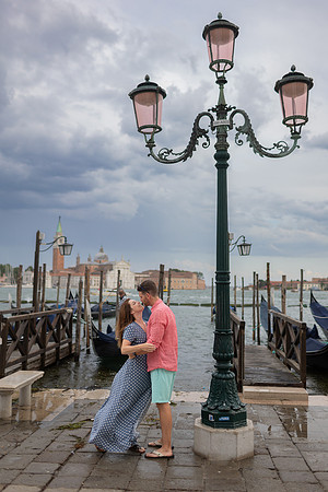 Couple sharing a kiss under a Venetian street lamp near the Grand Canal.
