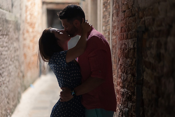 Silhouetted couple kissing in a dark Venice alley.