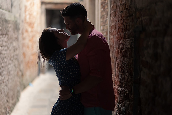Couple kissing in a hidden alley in Venice, with soft light highlighting their moment.