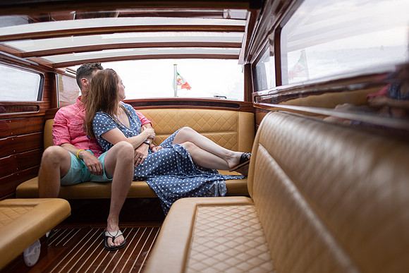 Couple sitting inside a luxurious wooden water taxi in Venice.