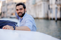 Man sitting on stone ledge by Venice lagoon