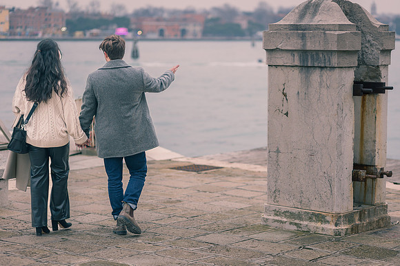Couple walking along Venice waterfront after engagement