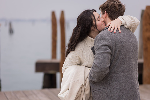 Couple sharing a kiss by Venice waterfront after proposal