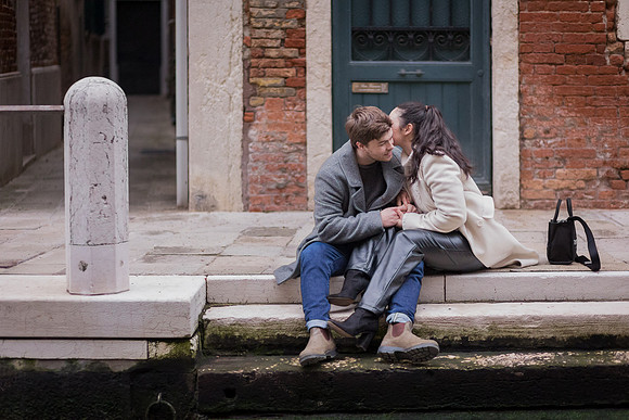 Couple sitting by Venice canal sharing quiet moment