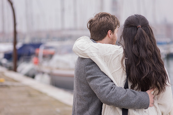 Couple sharing embrace by boats in Venice after proposal