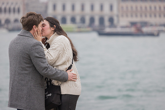 Couple kissing after surprise proposal by Venice waterfront