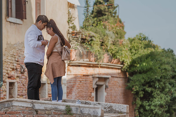 A groom-to-be kneels on one knee, proposing on Venice’s only bridge without railings.