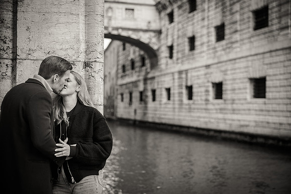 The couple walks hand in hand across a charming Venetian bridge after the rain.