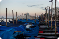 Couple standing near gondolas in Venice during golden hour.