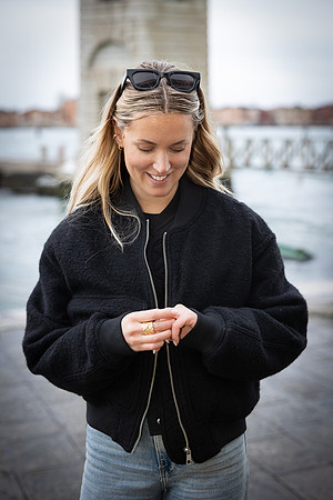 A bride-to-be looks down with a happy smile, cherishing the proposal moment.