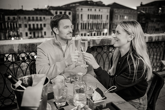 A soft-focus shot of the couple enjoying the Venice evening with a warm, golden glow.