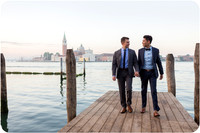 Couple walking together on a Venetian pier with a stunning sunrise view.
