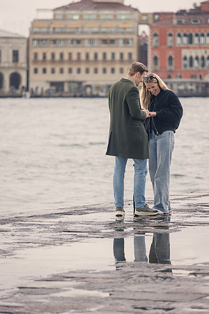 A couple embraces on a rain-kissed Venetian square, reflections shimmering beneath them.