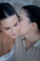 Soft-focus portrait of a same-sex couple, one kissing the other’s cheek.