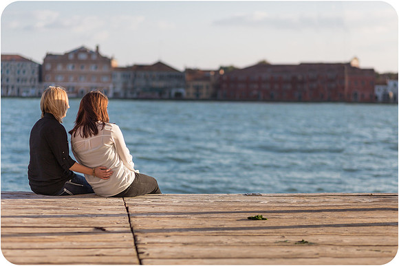 Couple kissing by the water in Venice during their same-sex honeymoon.