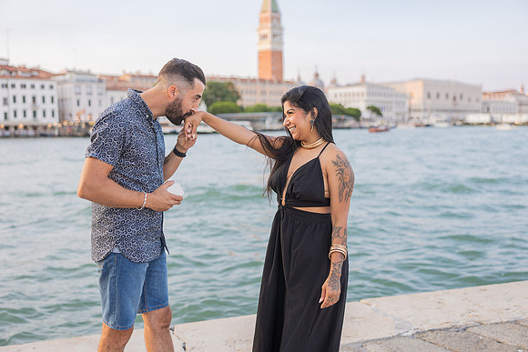 Groom kissing fiancée’s hand after successful surprise proposal.