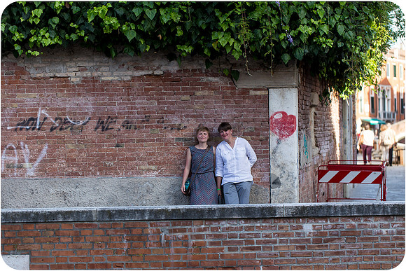 Lesbian woman sitting near a Venetian canal, reflecting during a summer afternoon.