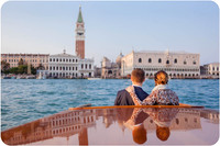 Couple kissing by the water with St. Mark’s Basilica in the background.