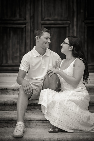 Engaged couple sitting on stone steps, sharing a lighthearted conversation