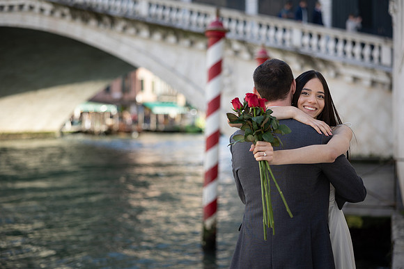 Woman posing with bouquet near the Rialto Bridge in Venice.