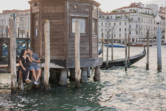 Couple seated on edge of Punta della Dogana dock, Grand Canal in view.