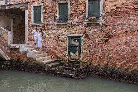 Newly engaged couple walking along a brick-lined canal in Venice