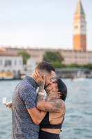 Couple kissing after sunset proposal with St. Mark’s tower in background.