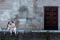 Engaged couple sitting together against an old Venetian wall.