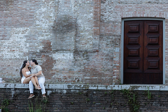 Engaged couple sitting together against an old Venetian wall.