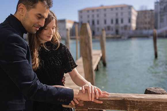 Couple standing near the water in Venice, sharing a romantic embrace.