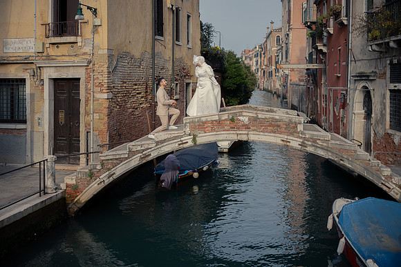 Bride-to-be standing on a Venetian bridge, looking at the canal.